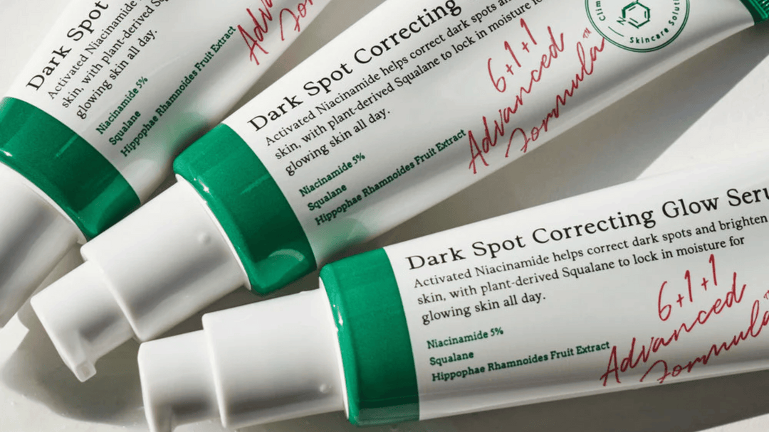 Tre tuber av Dark Spot Correcting Glow Serum med gröna lock, liggande på en ljus bakgrund. Tuberna är märkta med aktiva ingredienser som niacinamide och squalane för att förbättra hudens lyster och minska mörka fläckar.