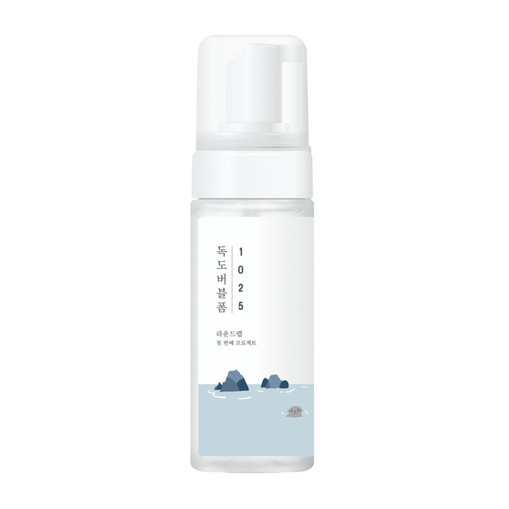1025 Dokdo Bubble Foam" er et ansiktsrenseprodukt fra ROUND LAB, pakket i en hvit pumpeflaske med enkel og ren design, prydet med tekst og minimalistiske illustrasjoner av havlandskap. 