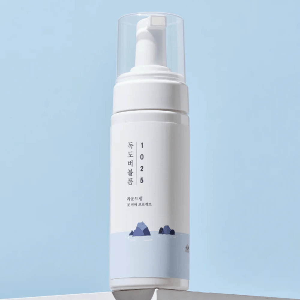  Produktet er en "1025 Dokdo Bubble Foam" fra ROUND LAB, pakket i en hvit pumpeflaske med minimalistisk design. Den er beregnet for dyprens av ansiktet uten irritasjon.