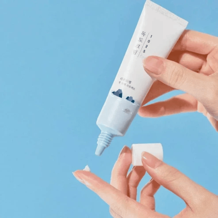 Round Lab 1025 Dokdo Eye Cream tube med lett krem som påføres på fingertuppen for skånsom pleie av sensitiv hud rundt øynene