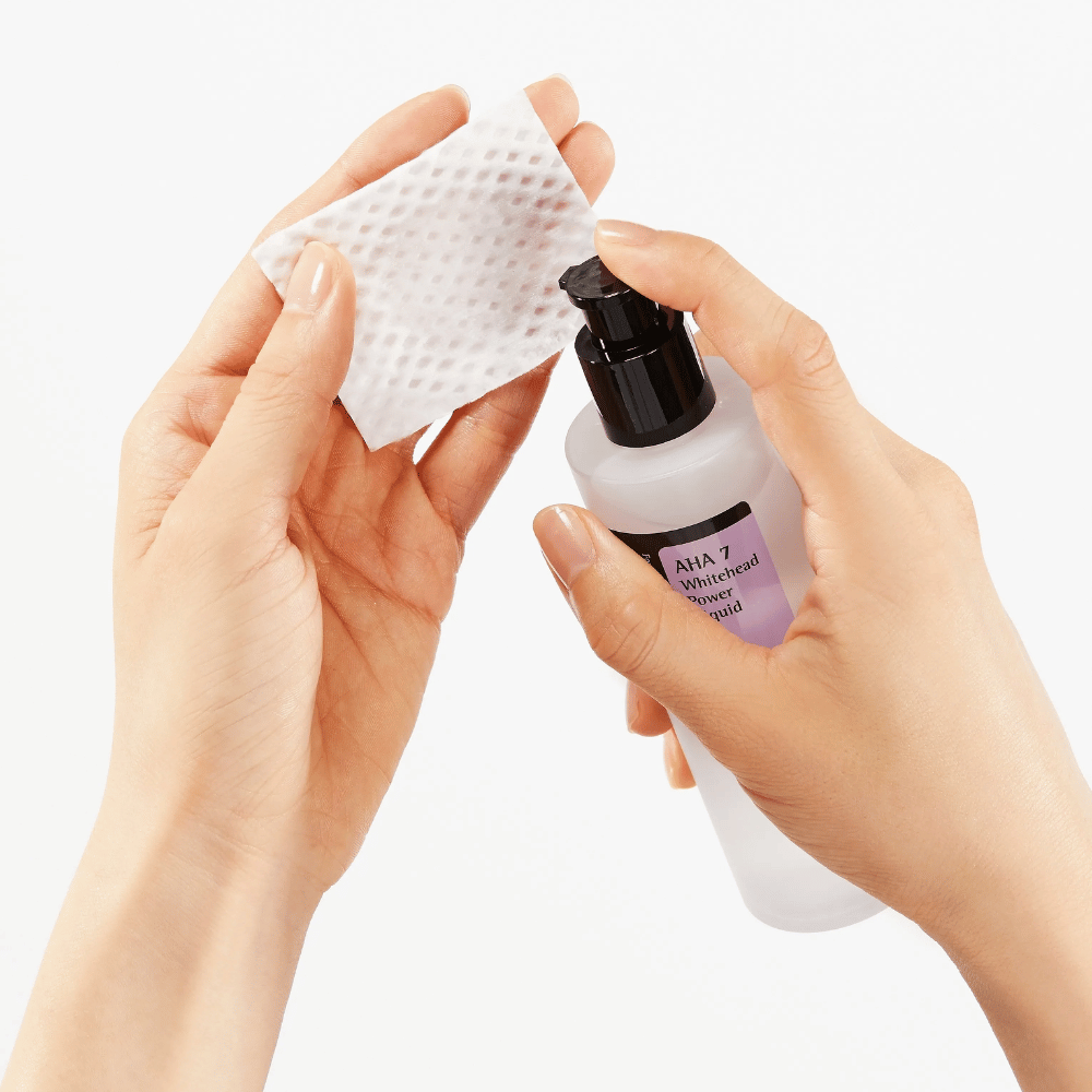 Påføring av COSRX AHA 7 Whitehead Power Liquid på bomullspad, eksfolierende toner med AHA for å fjerne døde hudceller og forbedre hudstrukturen.