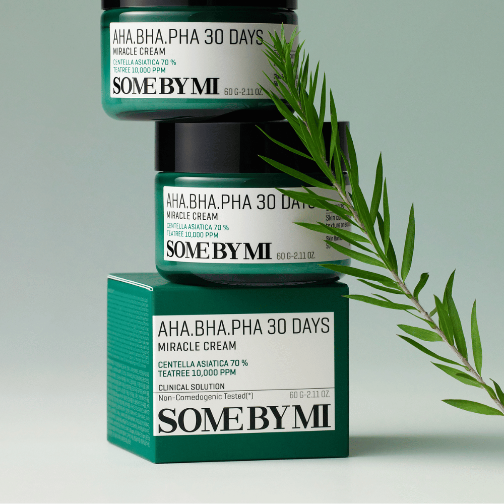 Et bilde som viser to krukker av "SOME BY MI AHA, BHA, PHA 30 Days Miracle Cream" stablet på en grønt tonet boks. Kremen, som er rik på centella asiatica og tea tree-olje, er designet for å forbedre hudens kvalitet og lindre problemhud. Virker fuktighetsgivende og beroligende.