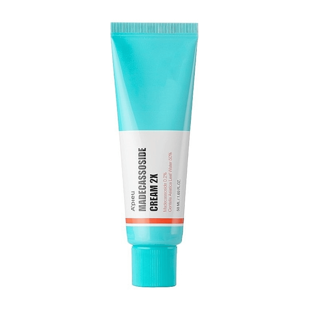 En tube med A'PIEU Madecassoside Cream 2X, med en lys turkis farge på toppen som går over til hvit mot bunnen. Tuben har tydelig tekst som angir merke og produktnavn samt den aktive ingrediensen Madecassoside 2%. En oransje aksentfarge går som en stripe rundt tuben. Produktet ser ut til å være en hudkrem som er rettet mot hudpleie og reparasjon. Bakgrunnen er nøytral for å holde fokus på produktet.