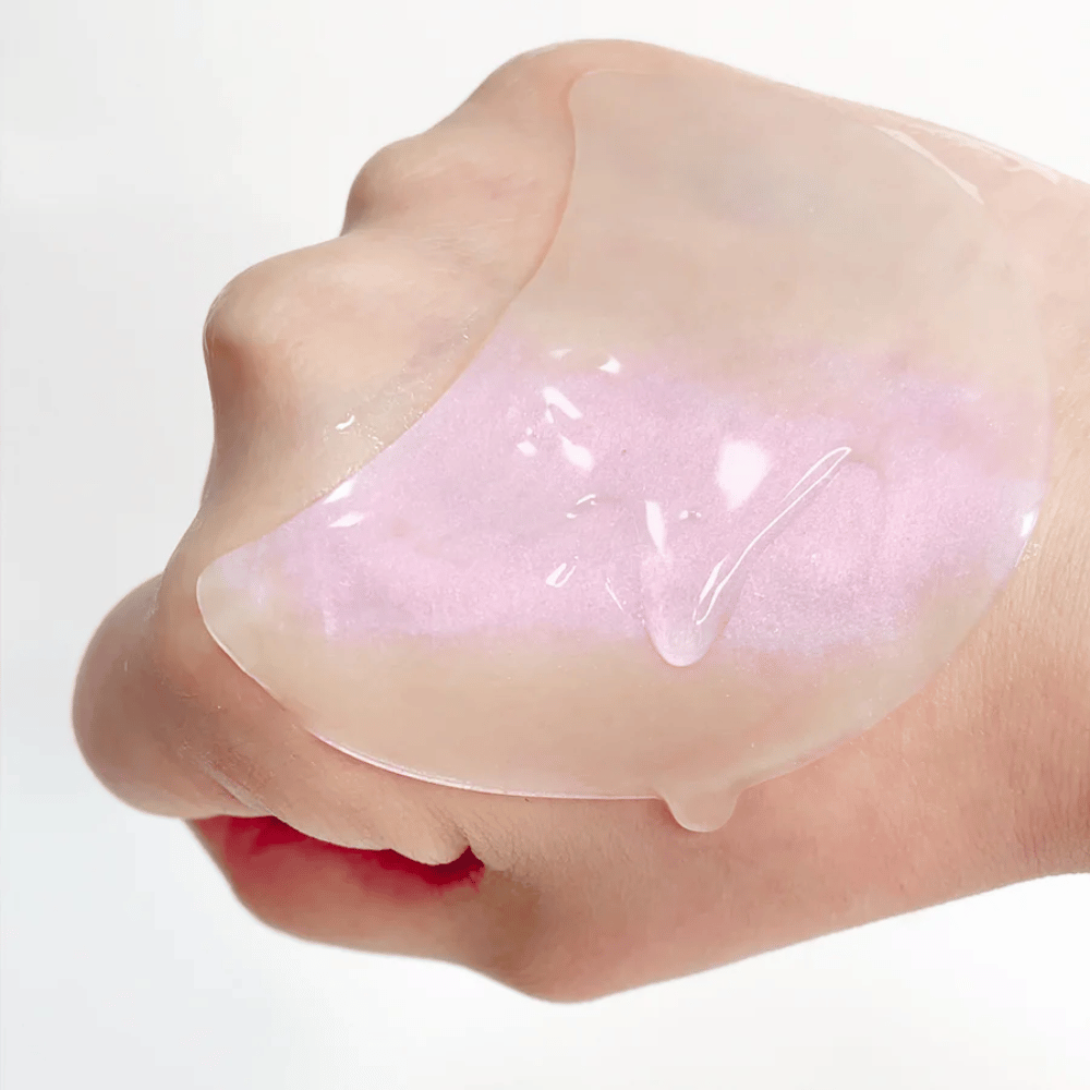 Rosa hydrogel eye patch med retinol vises på en hånd, fuktighetsgivende og glødgivende formula.