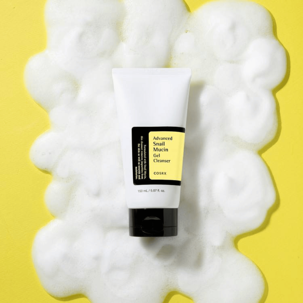 COSRX Advanced Snail Mucin Gel Cleanser 150 ml omgitt av rikelig skum på gul bakgrunn – mild koreansk ansiktsrens med snegleslim for fuktighet og glød.