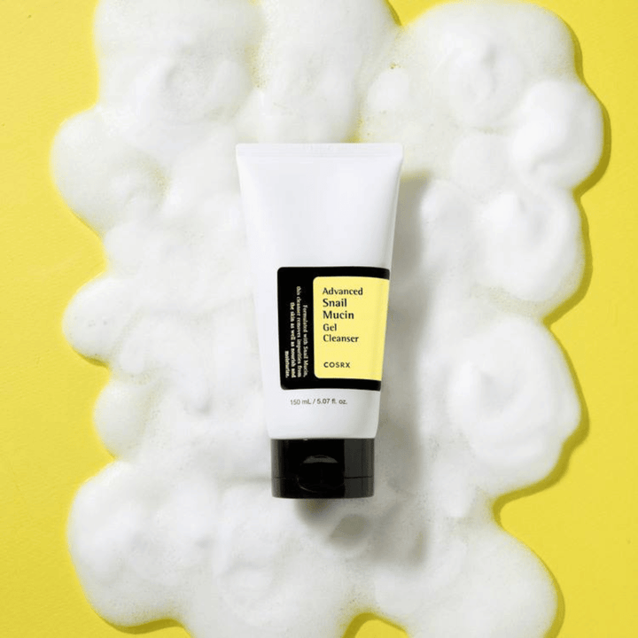 COSRX Advanced Snail Mucin Gel Cleanser 150 ml omgitt av rikelig skum på gul bakgrunn – mild koreansk ansiktsrens med snegleslim for fuktighet og glød.