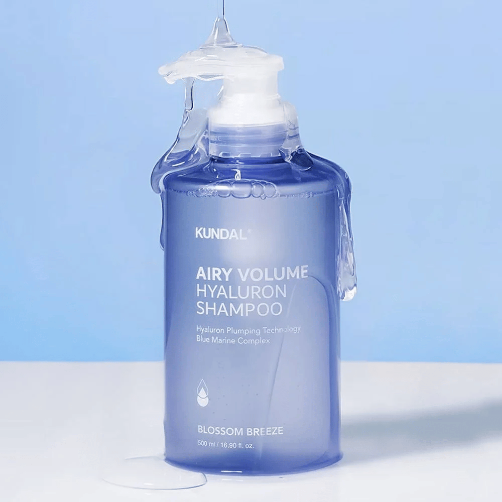 KUNDAL Airy Volume Hyaluron Shampoo Blossom Breeze i blå pumpeflaske, med hyaluron og Blue Marine Complex, fotografert med rennende vann.