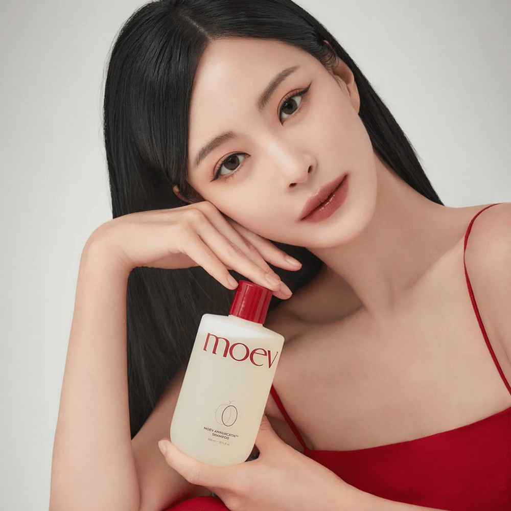 Kvinne med langt, glansfullt hår holder MOEV Annurcatin Shampoo – en koreansk sjampo som fukter, styrker og beskytter håret med naturlige ingredienser.