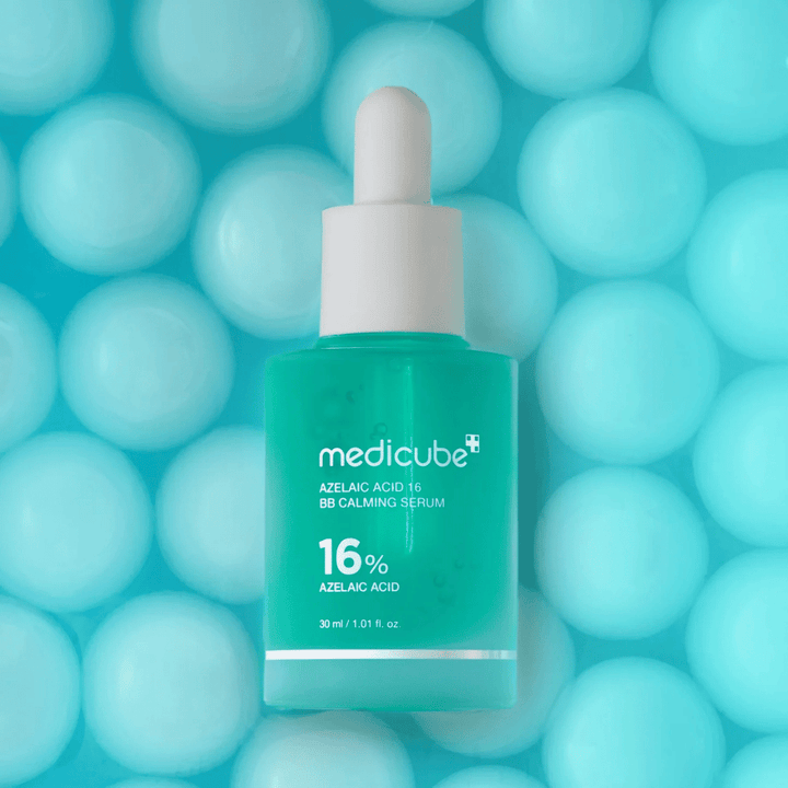 Kampanjebilde av Medicube Azelaic Acid 16 BB Calming Serum mot turkis bakgrunn med myke sfærer som symboliserer fuktighet, beroligende effekt og jevn hudstruktur.