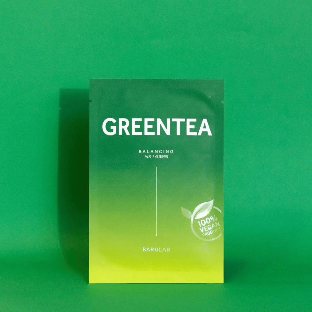 En pakke fra BARULAB for en "GREENTEA Balancing" maske, merket som "100% Vegan Product". Pakningens farge går fra mørkegrønn øverst til lysere grønn nederst, mot en ensartet grønn bakgrunn.