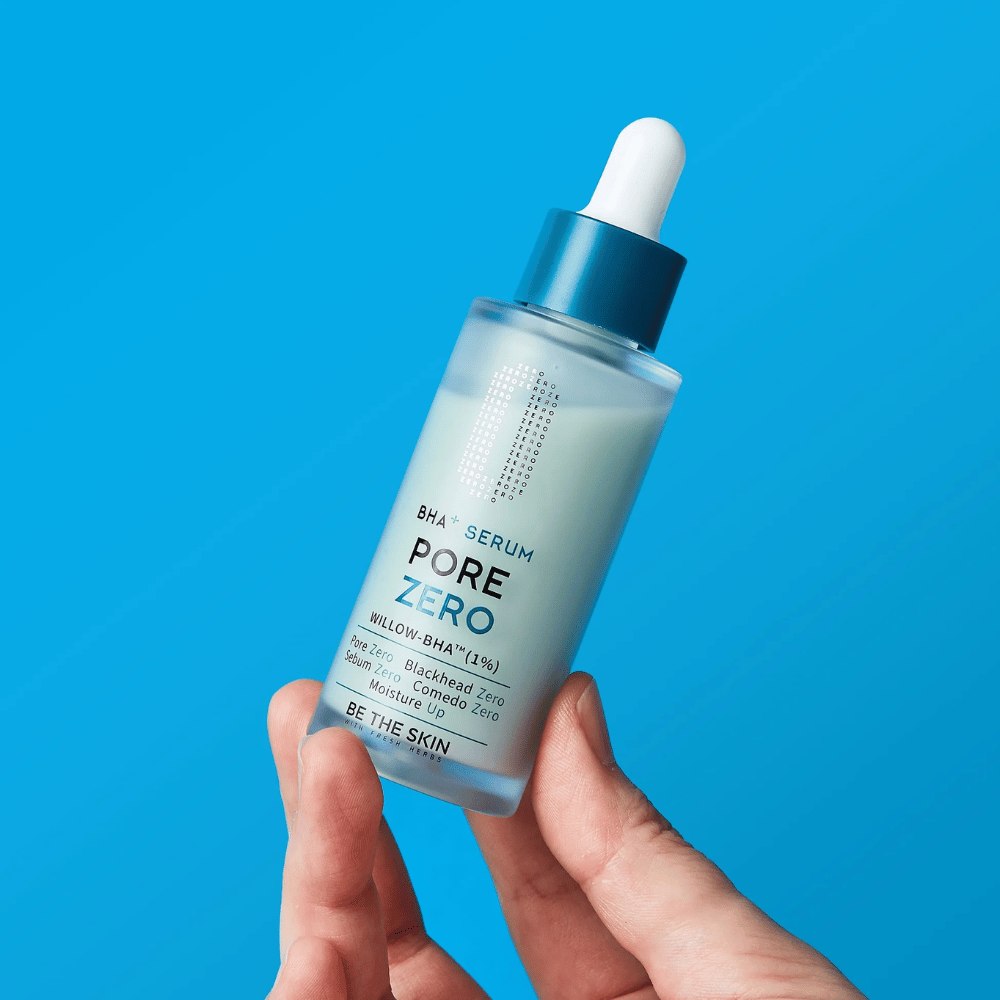 Be The Skin BHA+ Pore Zero Serum holdes i hånden mot blå bakgrunn