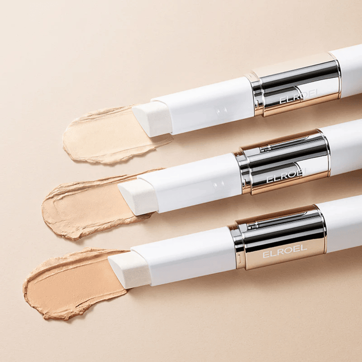 ELROEL Blanc Cover Cream Stick concealer med innebygd børste, flere stifter på rad som viser produktets design og påføring.