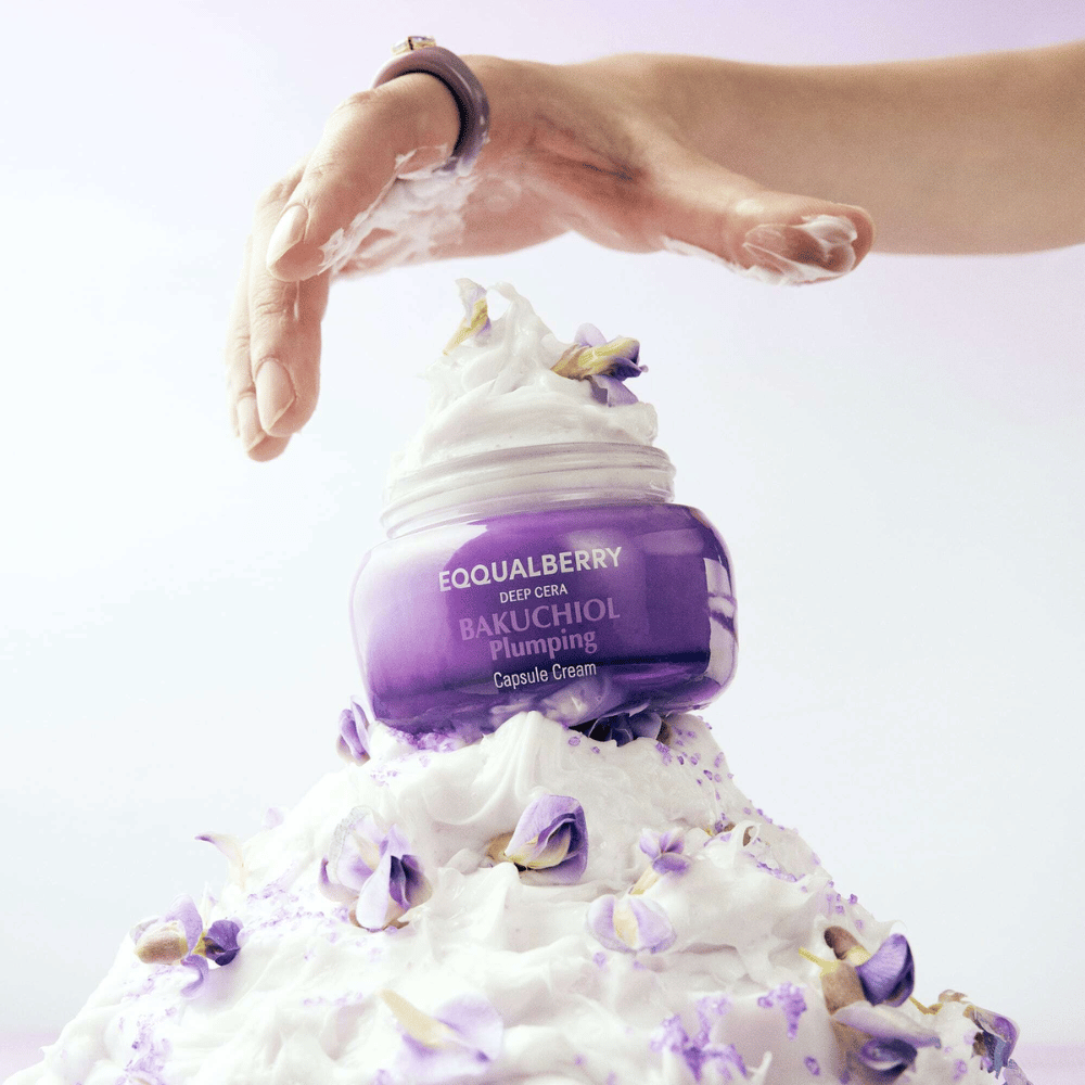 EQQUALBERRY Bakuchiol Plumping Capsule Cream plassert oppå en haug med pisket krem med blomsterblader – symboliserer fuktighet og pleie.