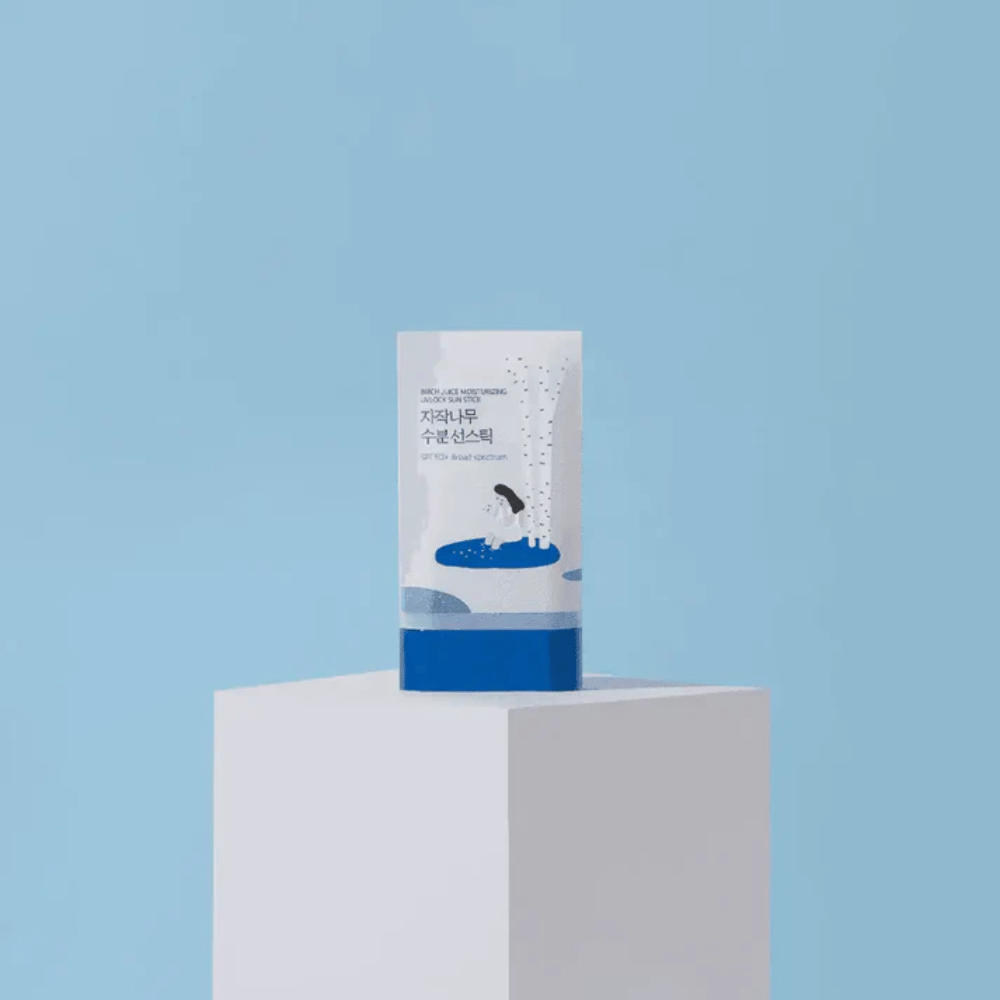 ROUND LAB Birch Juice Moisturizing Sun Stick SPF50+ står på pidestall mot blå bakgrunn – fuktgivende solbeskyttelse i stickformat