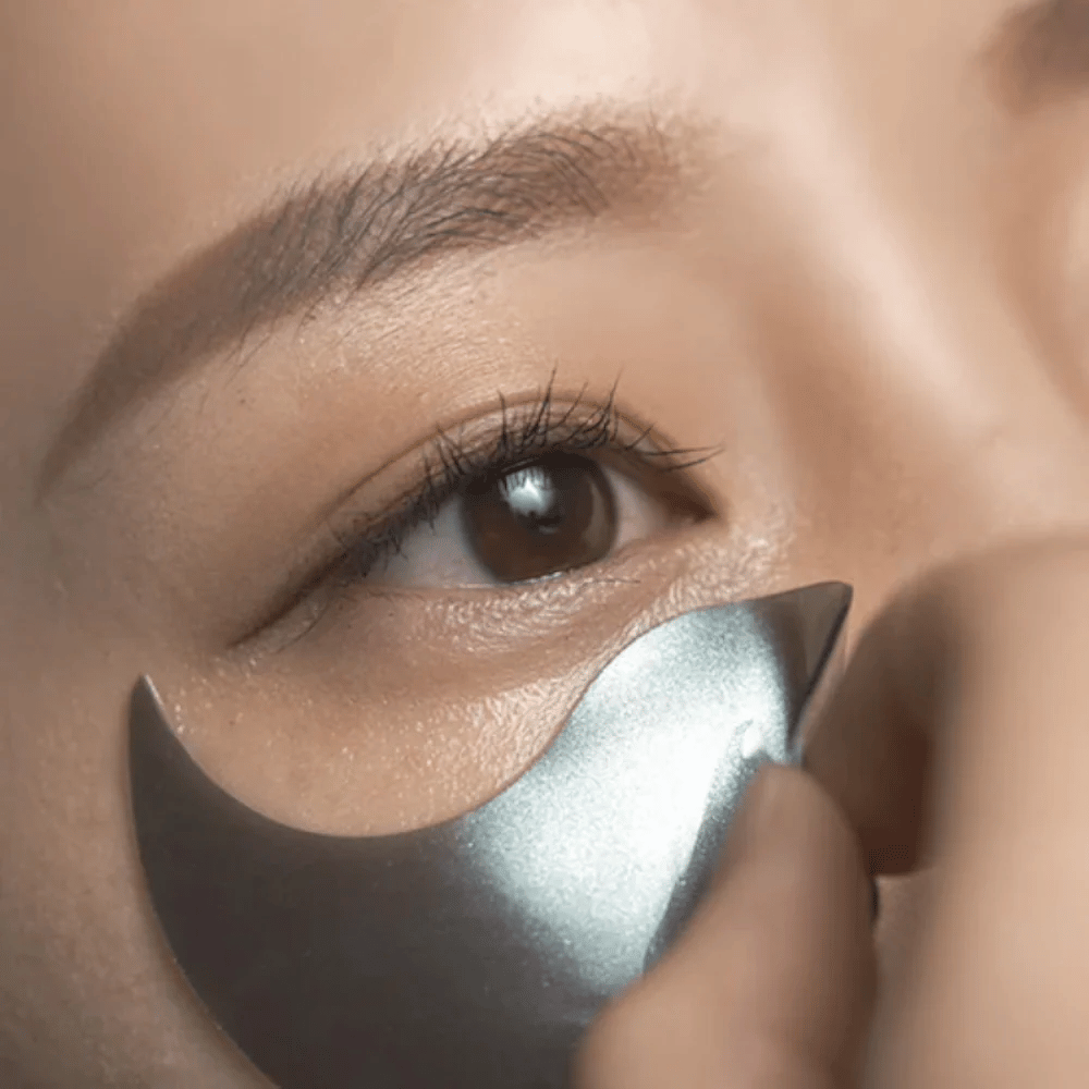 Detaljert bilde der en svart hydrogel eye patch påføres under øyet. Bildet viser den tette passformen og den svalende følelsen rundt øyeområdet.