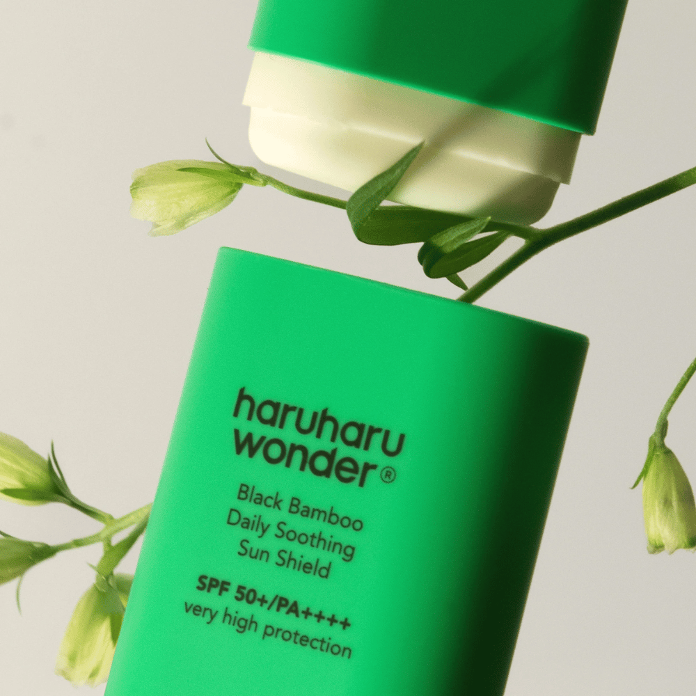 Nærbilde av Haruharu Wonder Black Bamboo Daily Soothing Sun Shield – en grønn solbeskyttelse i stiftformat med SPF 50+ PA++++, omgitt av grønne plante-detaljer.