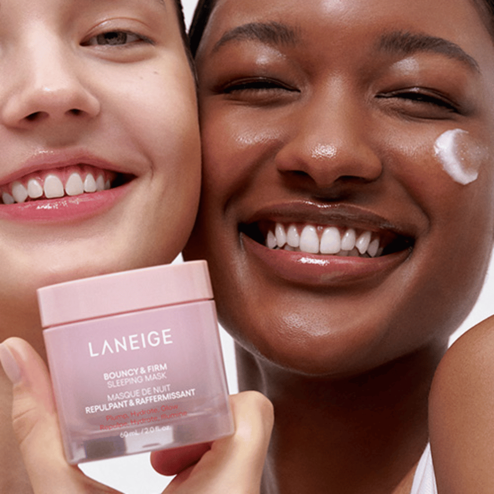 To personer smiler og holder i Laneige Bouncy & Firm Sleeping Mask. Den ene har påført masken på kinnet sitt, og produktet vises tydelig i deres hender. Masken er i en rosa krukke og markedsføres som "Plump, Hydrate, Glow."]