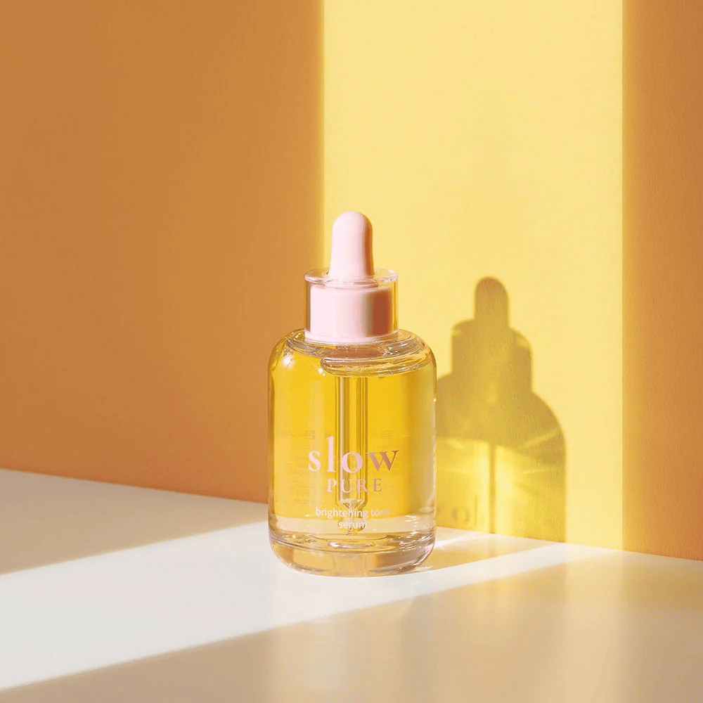 Slow Pure Brightening Tone Serum i solfylt gult lys, symboliserer glans og energi for huden.