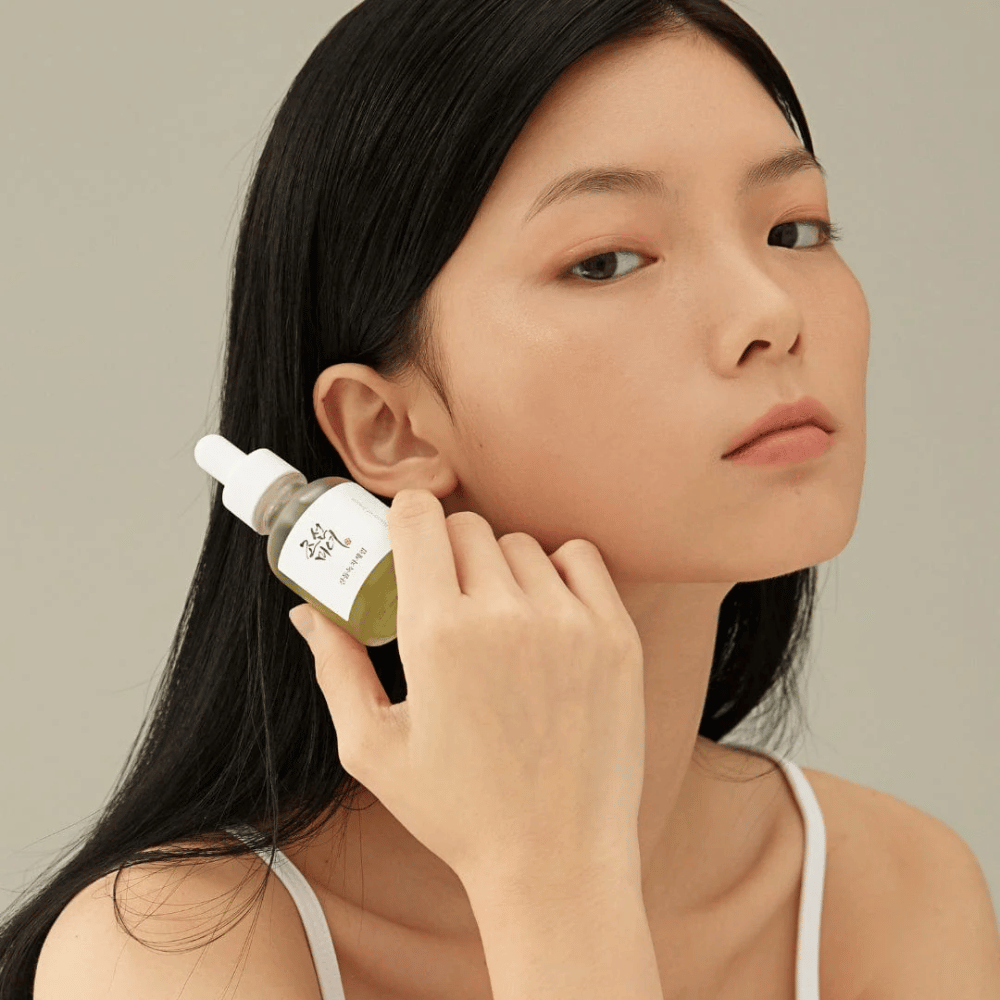 Modell holder Beauty of Joseon Calming Serum ved kinnet – grønn te og panthenol som styrker hudbarrieren.