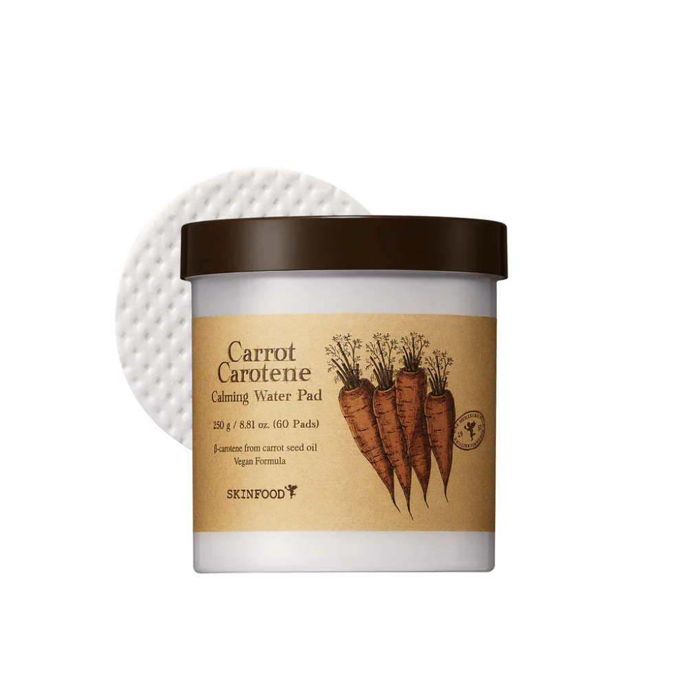 En boks "Carrot Carotene Calming Water Pad" fra SKINFOOD. Boksen inneholder 60 pads og er merket med et bilde av gulrøtter. Produktet, som er basert på gulrotfrøolje, er vegansk og designet for å berolige huden.