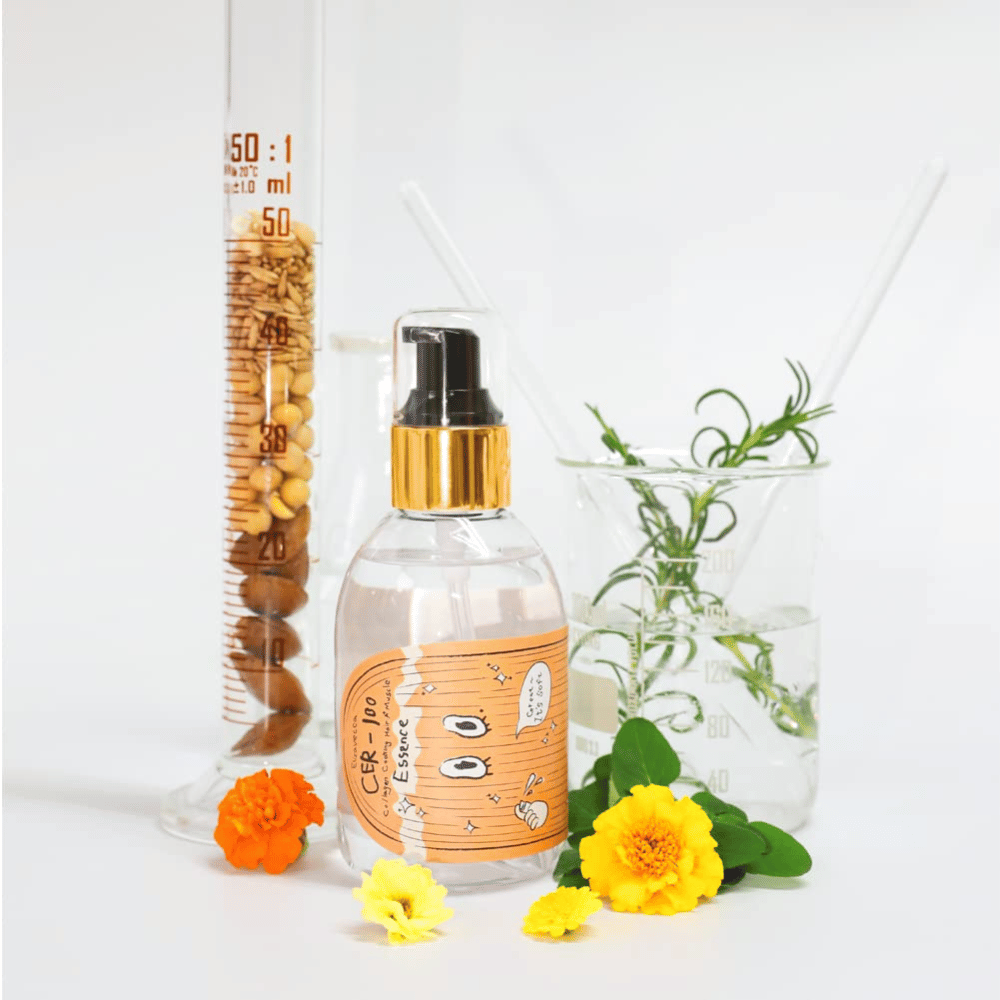 CER-100 Hair Essence sammen med blomster og laboratorieglass som fremhever ingredienser og hårpleie.