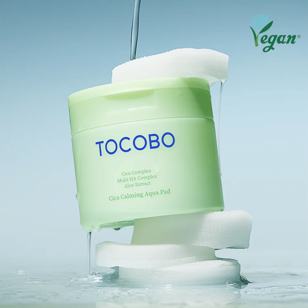 TOCOBO Cica Calming Aqua Pad plassert mellom toner pads med rennende essens. Vegan-symbolet understreker produktets veganske formulering og hudvennlige profil.
