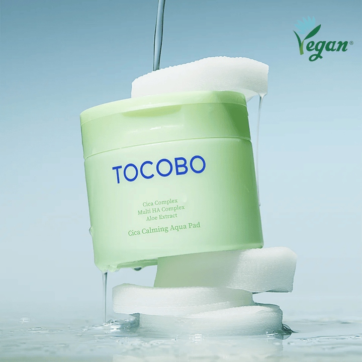 TOCOBO Cica Calming Aqua Pad plassert mellom toner pads med rennende essens. Vegan-symbolet understreker produktets veganske formulering og hudvennlige profil.