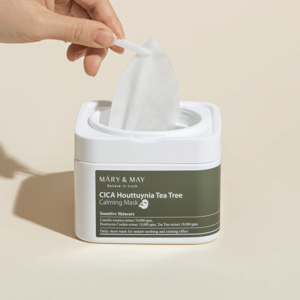 Hånd som drar opp en sheetmask fra Mary & May Cica Houttuynia Tea Tree Calming Mask-krukke – beroligende ansiktsmaske for sensitiv hud med Cica og Tea Tree-ekstrakt.