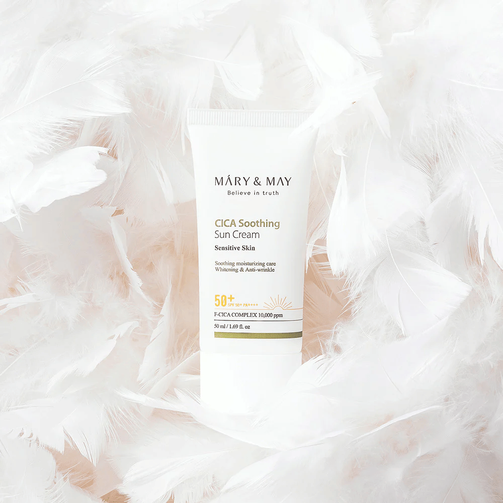 Mary&May CICA Soothing Sun Cream omgitt av myke hvite fjær. Bildet formidler en følelse av skånsomhet, komfort og lett formel tilpasset sensitiv hud.