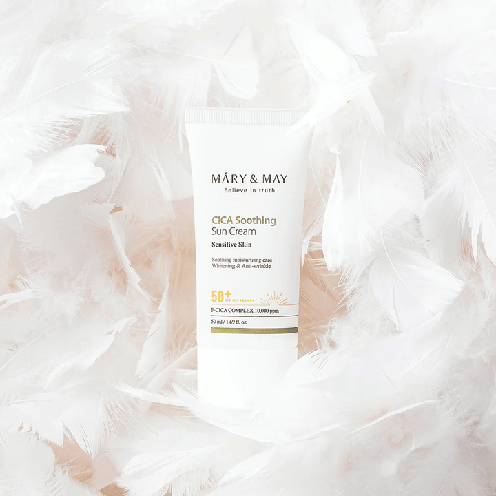 Mary&May CICA Soothing Sun Cream omgitt av myke hvite fjær. Bildet formidler en følelse av skånsomhet, komfort og lett formel tilpasset sensitiv hud.