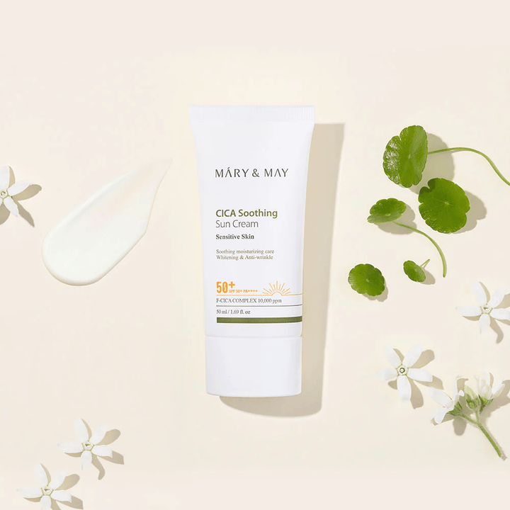 Mary&May CICA Soothing Sun Cream SPF50+ PA++++ presentert sammen med en kremtekstur, centella-blader og hvite blomster. Bildet fremhever produktets beroligende egenskaper og fokus på sensitiv hud.