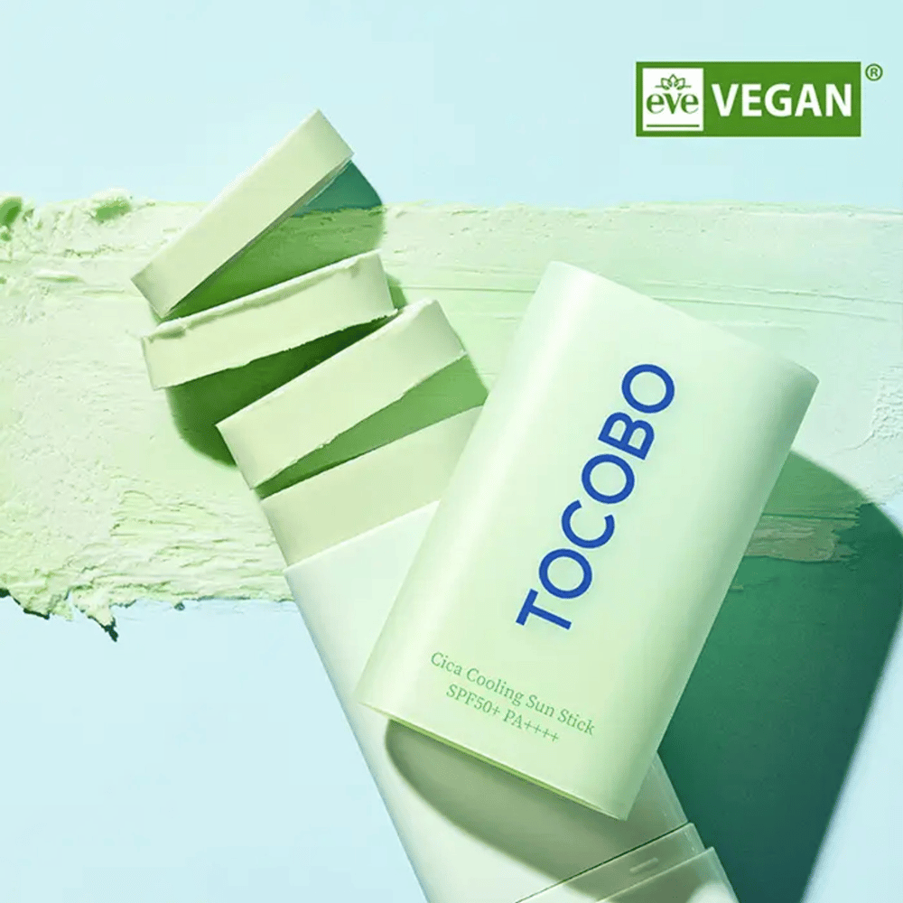 Tocobo Cica Cooling Sun Stick SPF50+ PA++++ i lysegrønn emballasje med veganmerking (EVE VEGAN), liggende på et lag av grønn solstift.