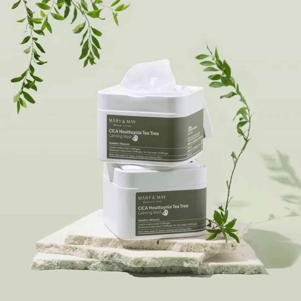 To krukker Mary & May Cica Houttuynia Tea Tree Calming Mask plassert på naturstein med grønne planteelementer – beroligende sheetmasker for sensitiv hud.