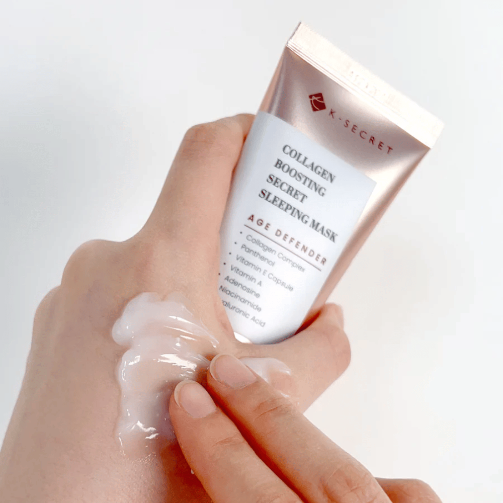 En hånd holder i Collagen Boosting Secret Sleeping Mask mens den andre påfører en generøs mengde krem på oversiden av hånden – viser produktets konsistens og påføring.