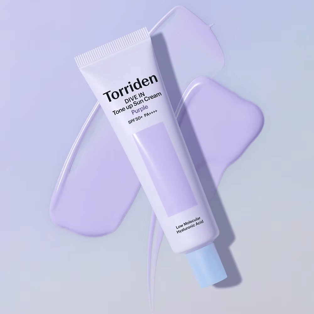 Torriden DIVE IN Tone Up Sun Cream Purple plassert på utsmurt lilla krem som fremhever den toneutjevnende og glødgivende effekten.