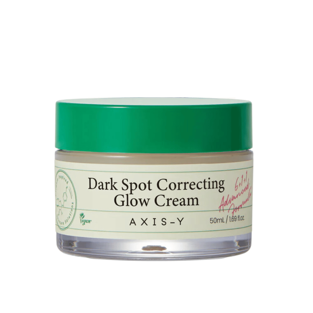 En boks med "AXIS-Y Dark Spot Correcting Glow Cream". Denne kremen er ment å korrigere mørke flekker og gi huden glød. Emballasjen er elegant med en gjennomsiktig bunn og et iøynefallende grønt lokk.