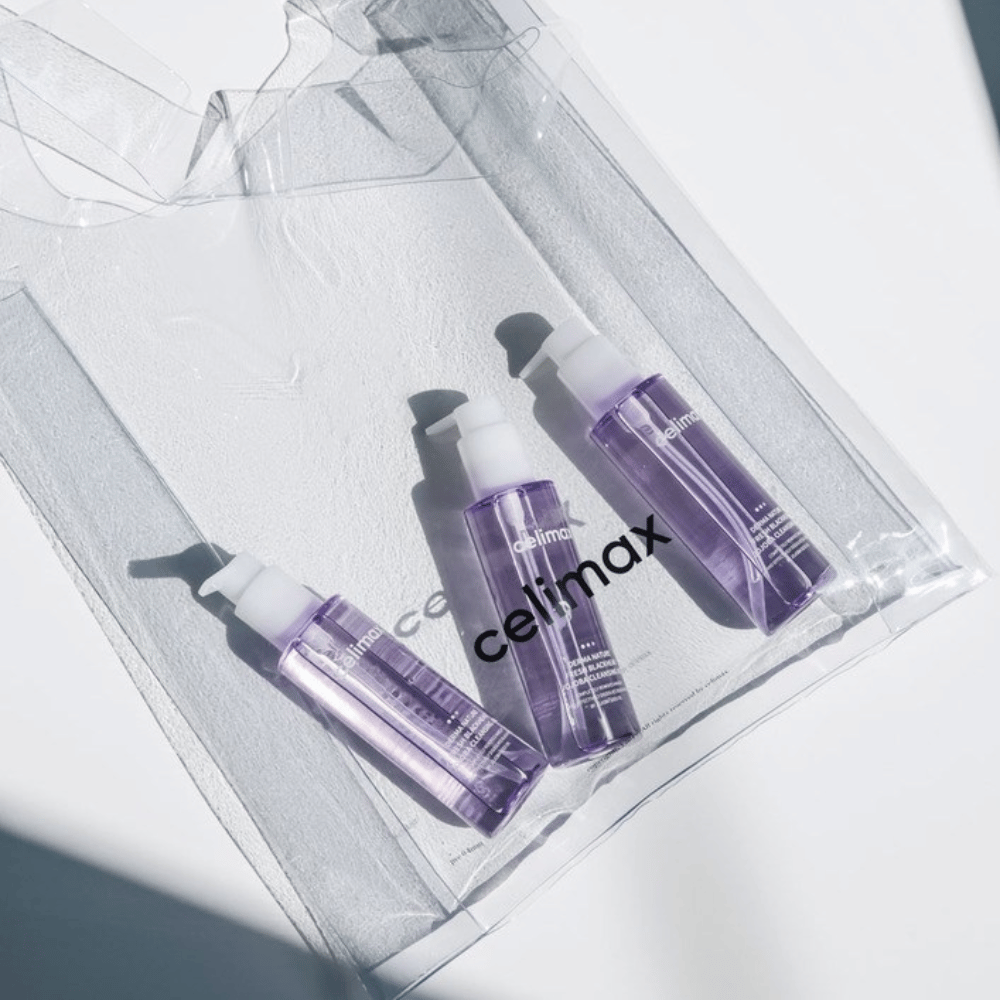 Tre flasker av Celimax Derma Nature Fresh Blackhead Jojoba Cleansing Oil i lilla emballasje, plassert i en gjennomsiktig pose med logoen 'celimax'.