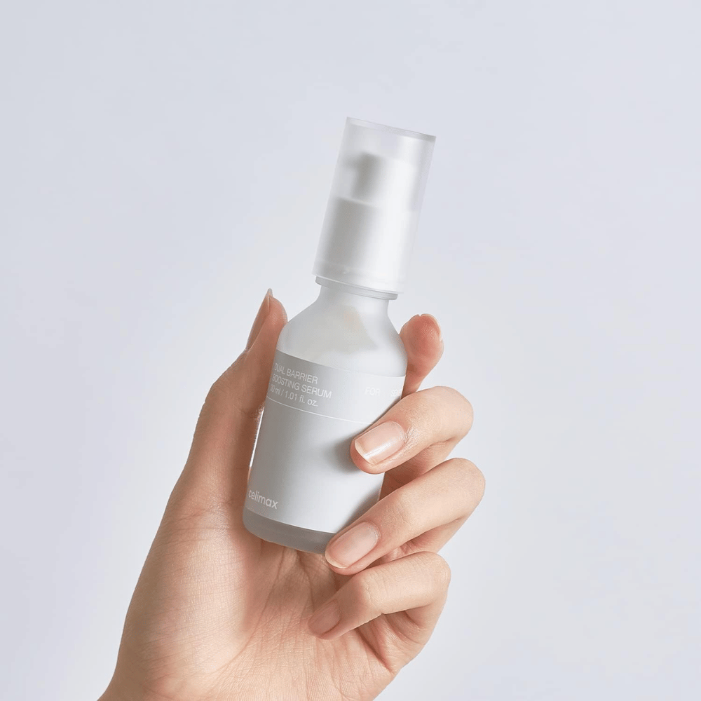 Celimax Dual Barrier Boosting Serum i hånd, minimalistisk emballasje som viser barriereforsterkende koreansk serum for sensitiv hud.
