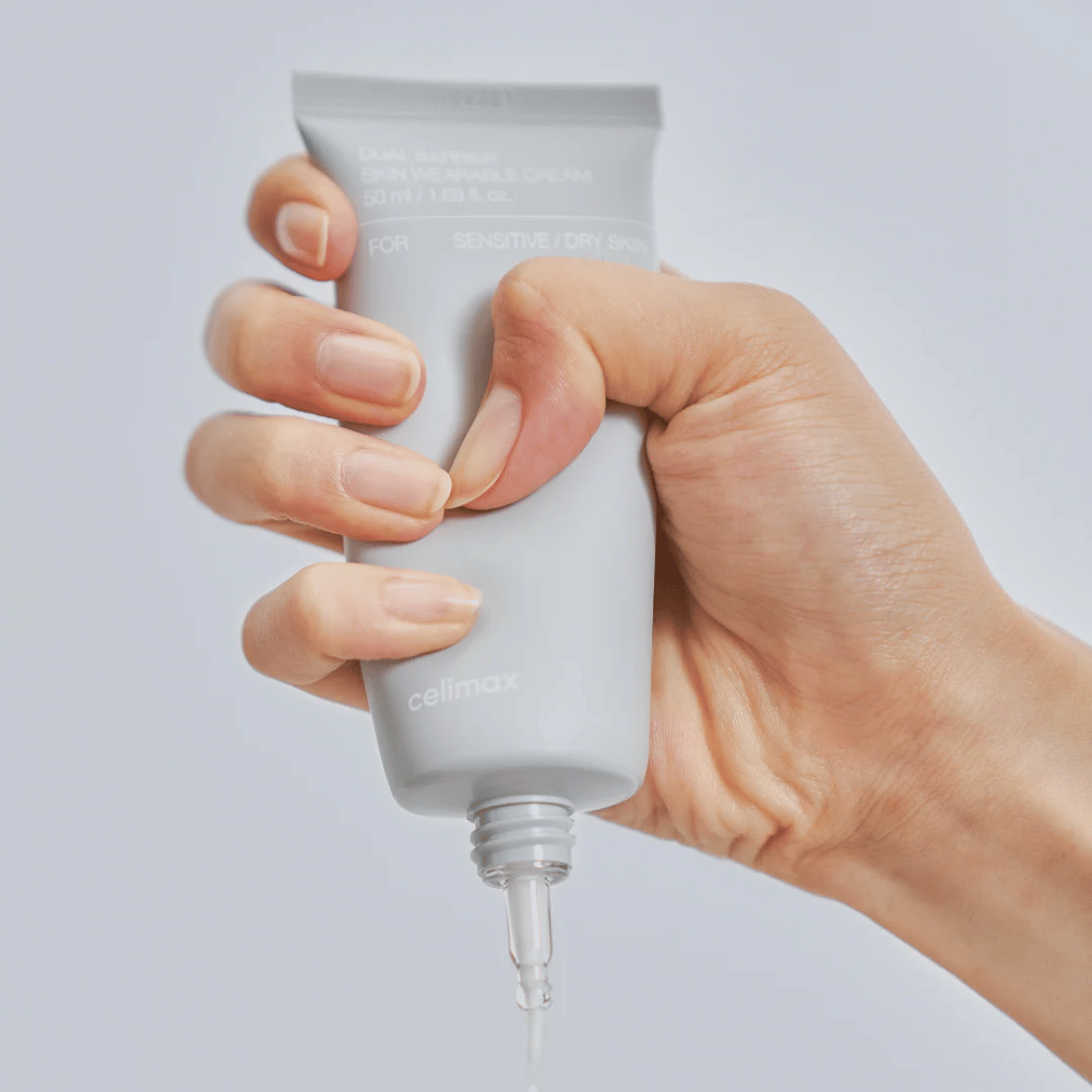 Hånd som påfører Celimax Dual Barrier Skin Wearable Cream, barriereforsterkende ansiktskrem for sensitiv og tørr hud som gir langvarig fuktighet og beskytter hudbarrieren.
