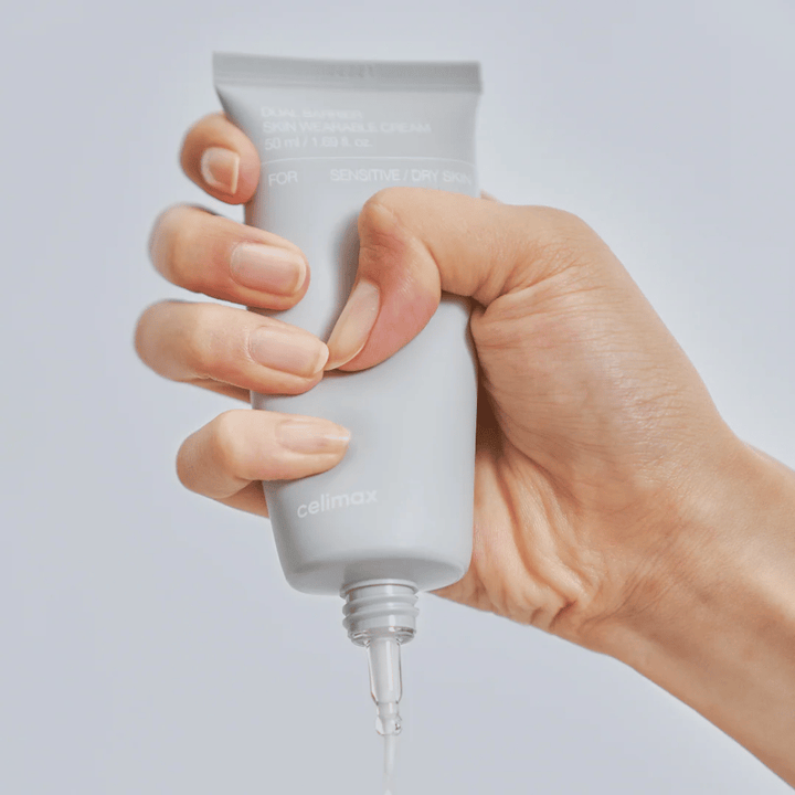 Hånd som påfører Celimax Dual Barrier Skin Wearable Cream, barriereforsterkende ansiktskrem for sensitiv og tørr hud som gir langvarig fuktighet og beskytter hudbarrieren.