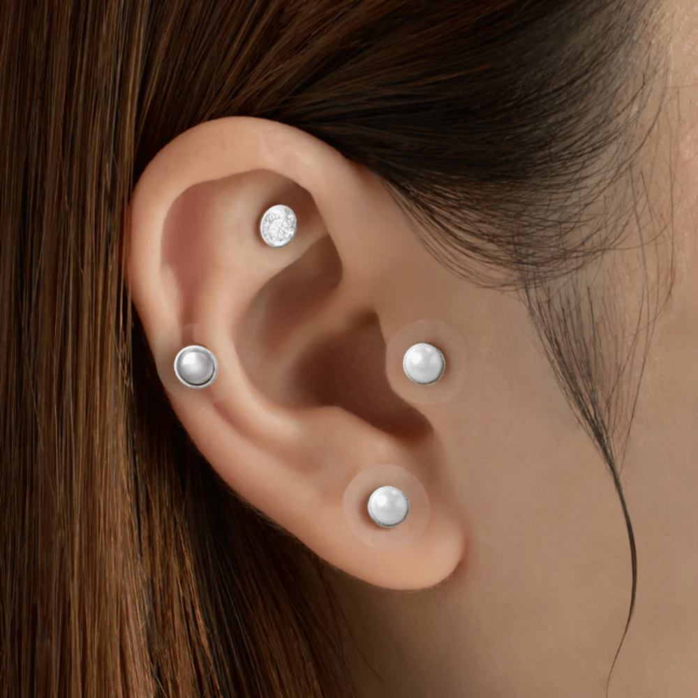 Nærbilde av et øre med flere RETURNITY Ear Therapy Acupressure Patch påført på ulike områder av øret for akupressur og et stilrent uttrykk.