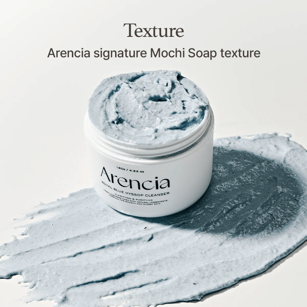 Åpen krukke med Arencia Fresh Blue Hyssop Rice Mochi Cleanser, plassert oppå et utsmurt lag av den blå, kremete rengjøringsformelen som viser dens mochi-lignende tekstur.