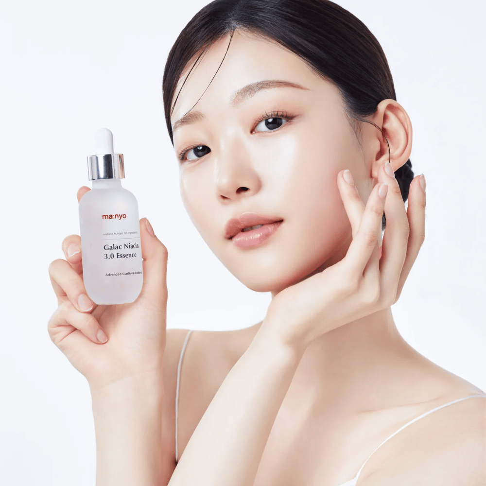 Kvinne med strålende hud holder Ma:nyo Galac Niacin 3.0 Essence – koreansk essens som gir jevnere hudtone og naturlig glød.