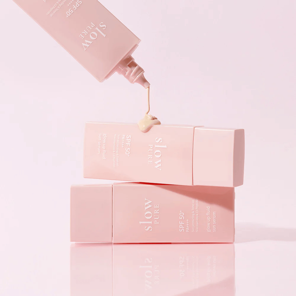 Slow Pure Glow Up Fluid Sun Serum med krem presset ut av flasken, viser lett og pleiende konsistens.