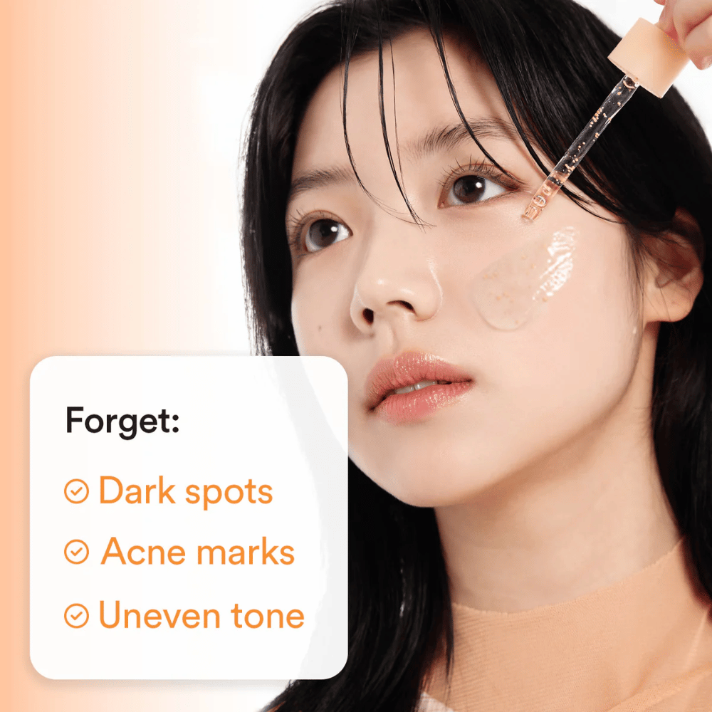 Kvinne påfører serum med pipette på kinnet. Teksten på bildet lister Fordeler: "Forget: Dark spots, Acne marks, Uneven tone".