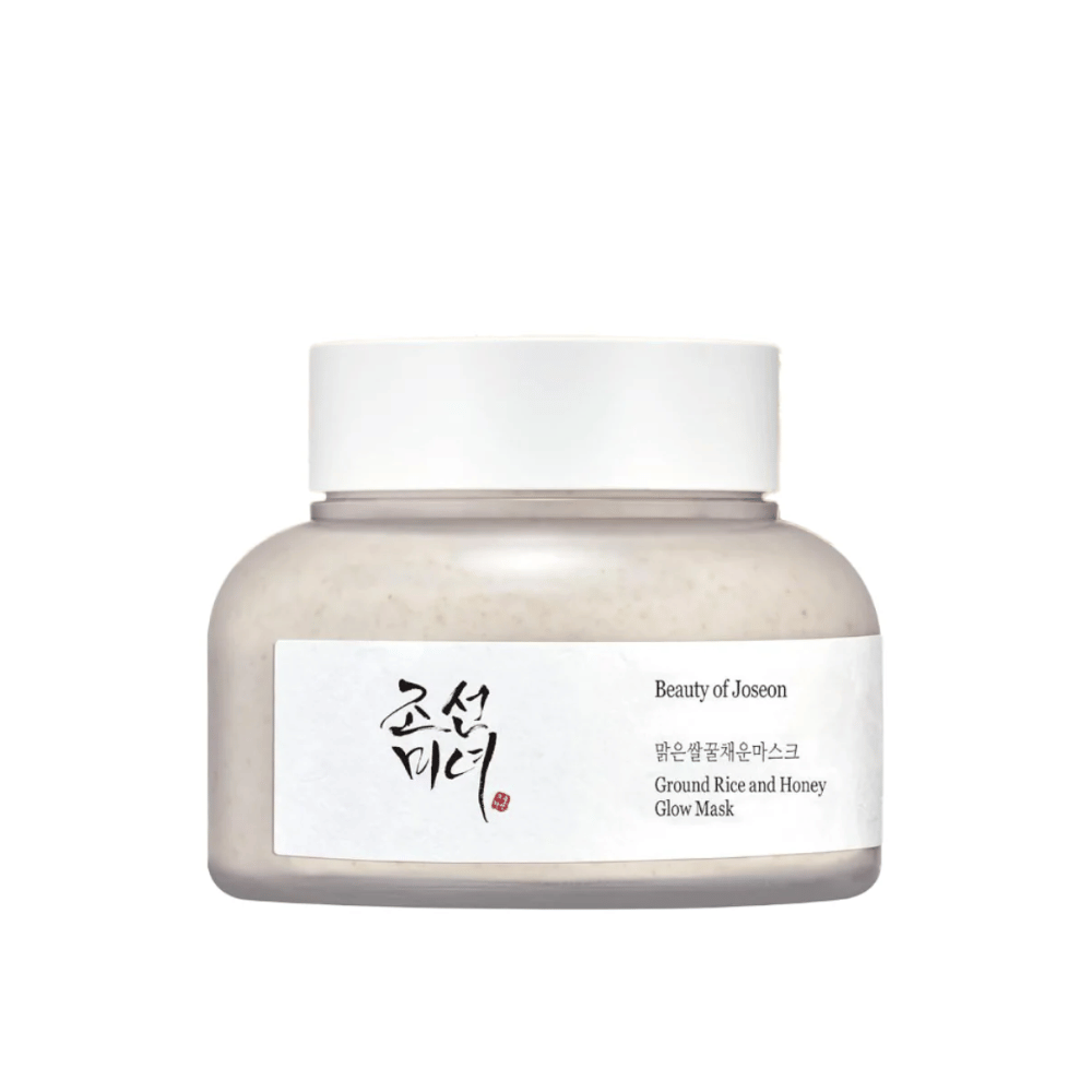 En boks "Beauty of Joseon Ground Rice and Honey Glow Mask". Emballasjen er enkel med en hvit kork og en etikett som presenterer produktnavnet og ingredienser på både koreansk og engelsk. Produktet er utformet for å gi glød og næring til huden.