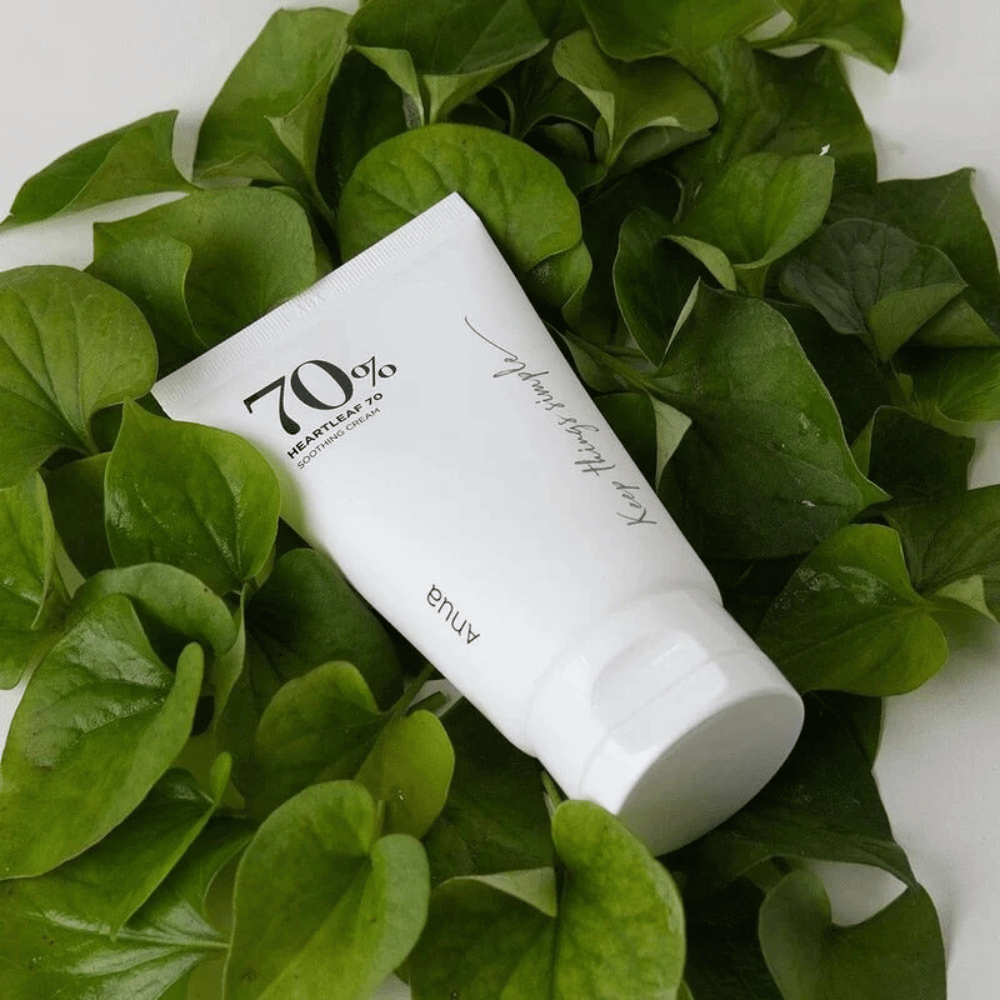 En tube av Heartleaf 70% Soothing Cream hviler på en seng av grønne blader.
