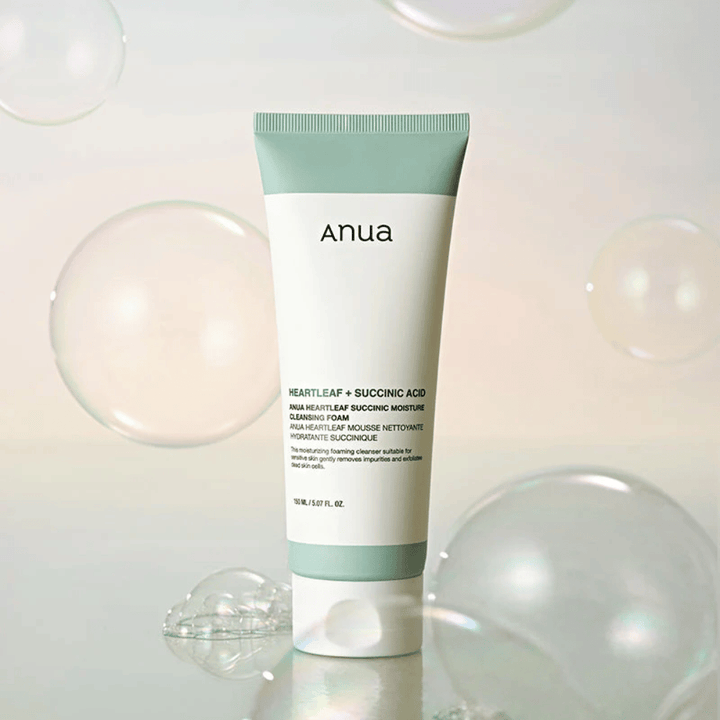 Produktbilde av Anua Heartleaf + Succinic Acid Moisture Cleansing Foam omgitt av transparente bobler. Bildet forsterker følelsen av mild rengjøring, friskhet og et luftig skum.