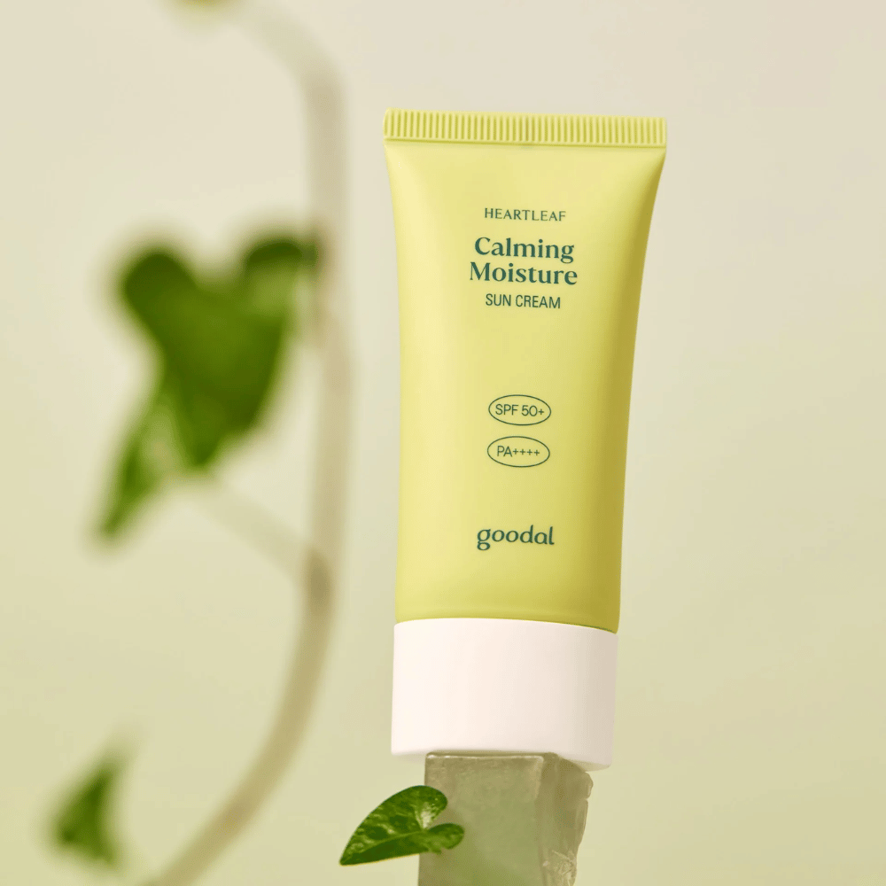 Goodal Heartleaf Calming Moisture Sun Cream SPF50+ PA++++ plassert på en glassplate med grønn plante i bakgrunnen – en beroligende solkrem for sensitiv hud.