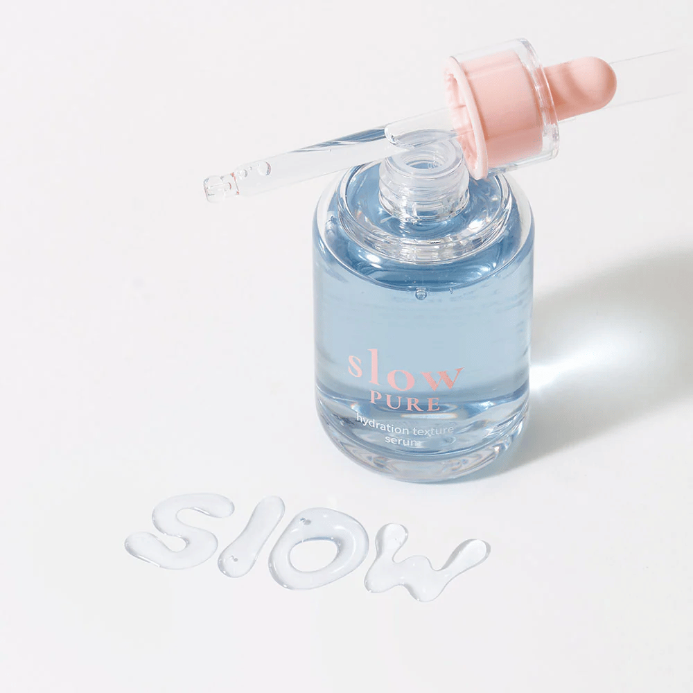 Slow Pure Hydration Texture Serum med åpen pipette, tekst skrevet i serum på overflaten: "Slow".
